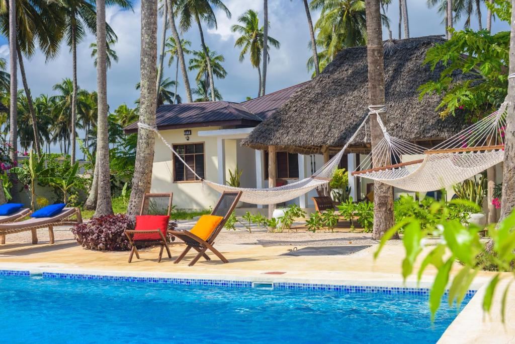 a resort with a swimming pool and hammocks at Magic Beach Villa in Kiwengwa