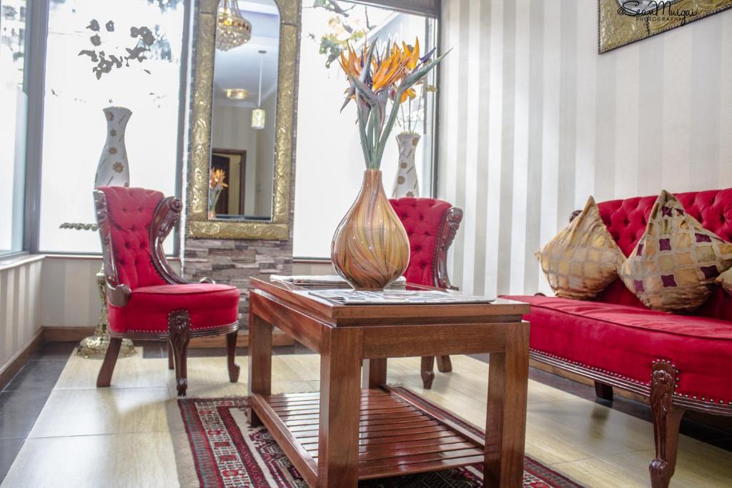 a living room with a red couch and a vase on a table at After 40 Hotel in Nairobi