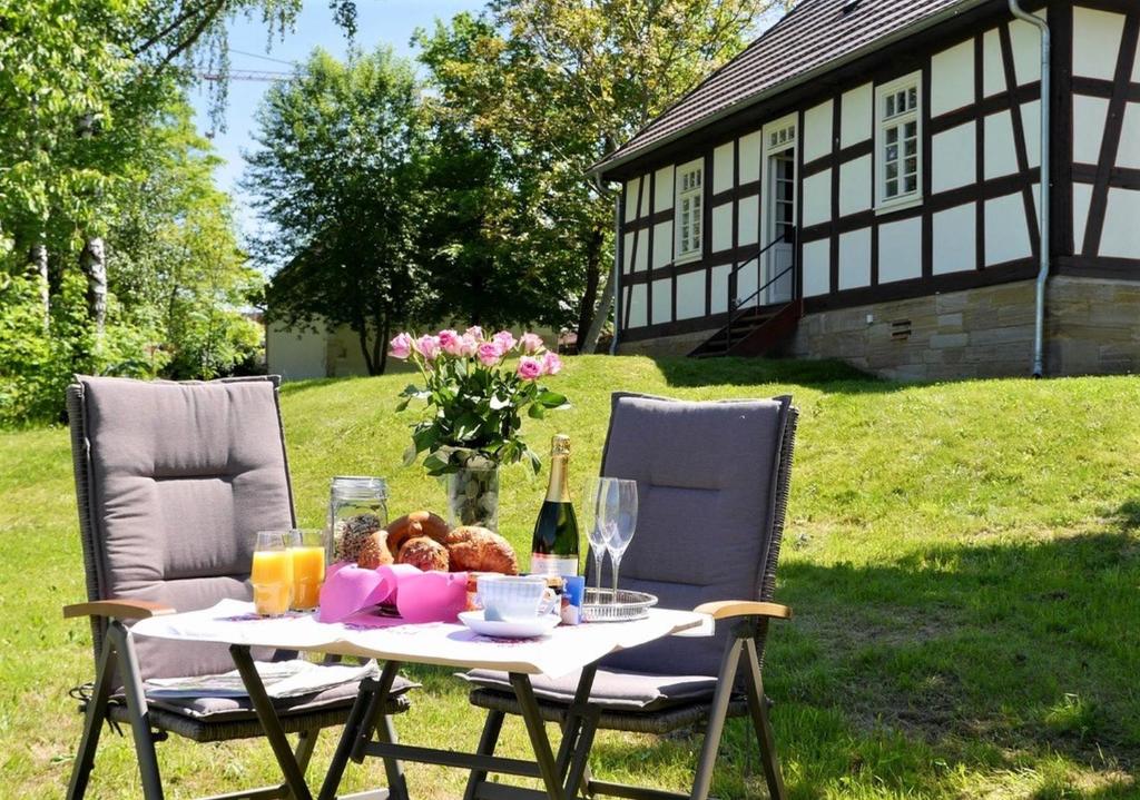 einen Tisch mit einem Korb mit Speisen und Getränken und ein Haus in der Unterkunft Gutshof Schäferhaus in Frielendorf