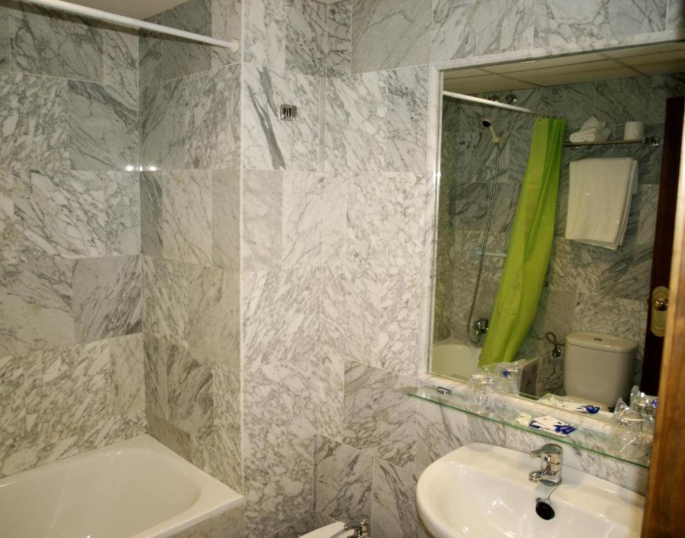 Baño blanco con lavabo y espejo en Hotel Al-Yussana, en Lucena