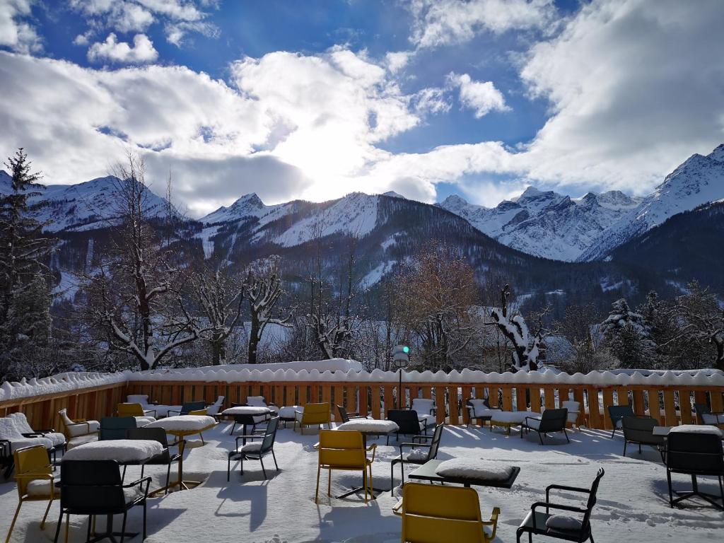 a patio with tables and chairs in the snow at Hôtel Restaurant Le Monêtier in Le Monêtier-les-Bains