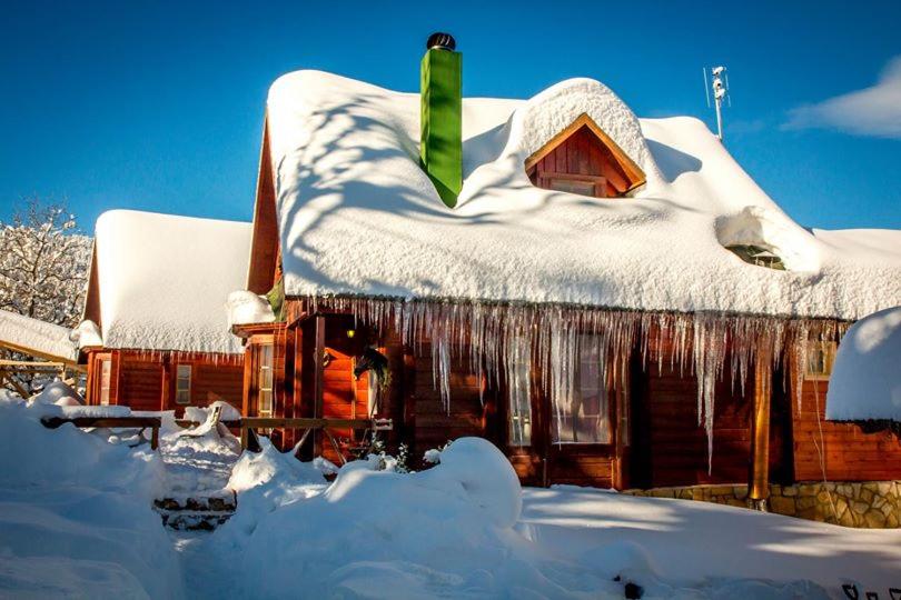 une maison recouverte de neige avec des icides sur elle dans l'établissement Kedra Village, à Kédra