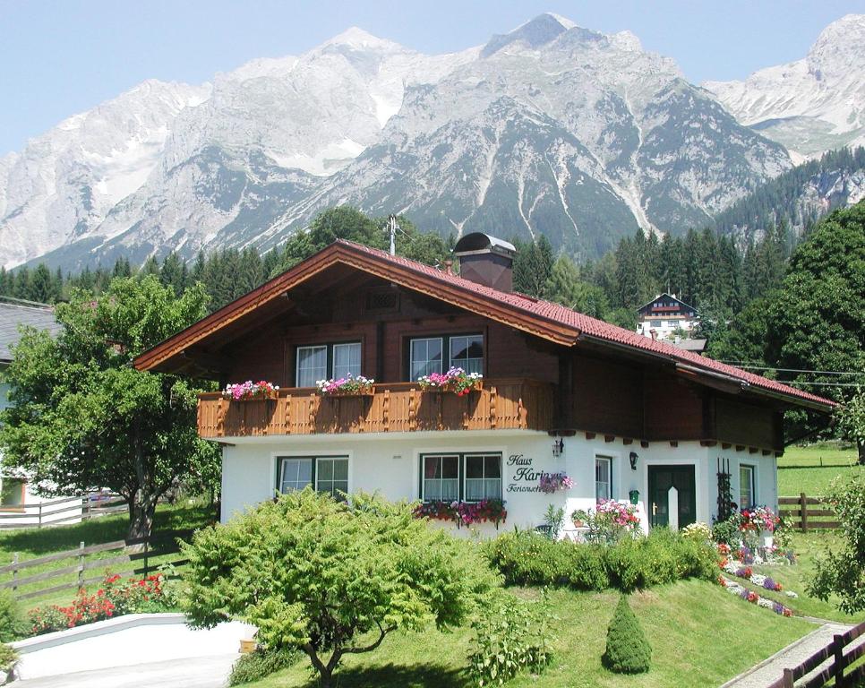 ein Haus mit Blumen auf dem Balkon vor den Bergen in der Unterkunft Ferienhaus Karin in Ramsau am Dachstein