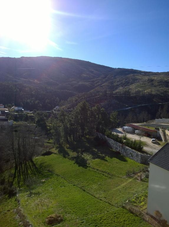 uma vista para um campo verde com o sol ao fundo em Monte Estrela em Sabugueiro