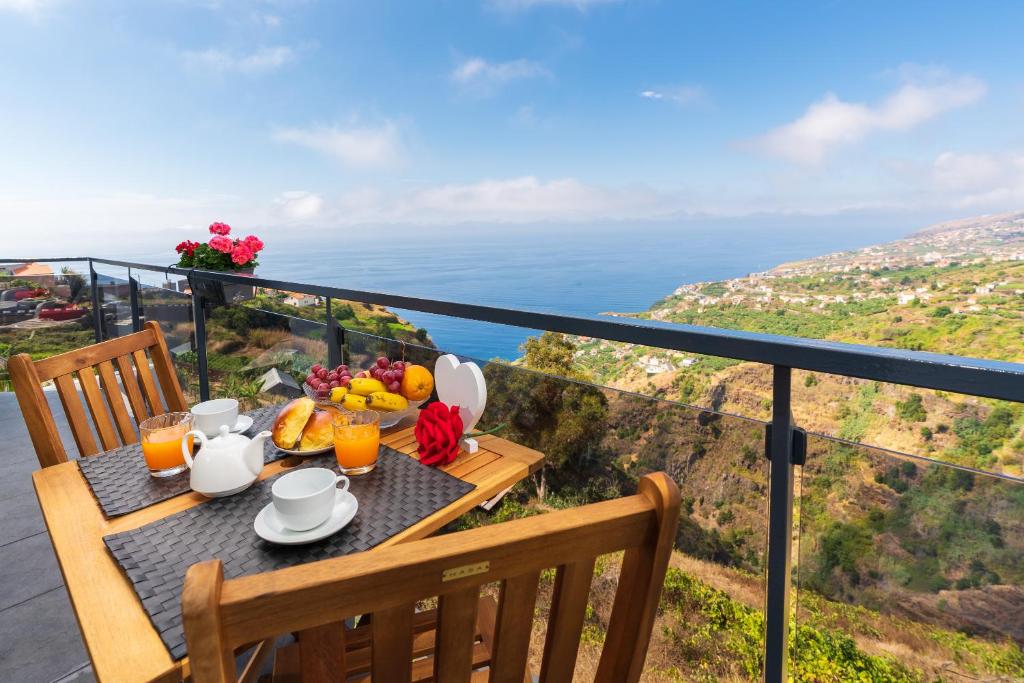 a table with a breakfast of fruit and juice on a balcony at Casa das Abertas in Calheta