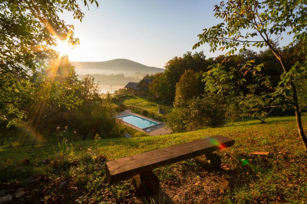 a wooden bench sitting in a park with the sun setting at Villa Jelenic by Bertovic in Ogulin
