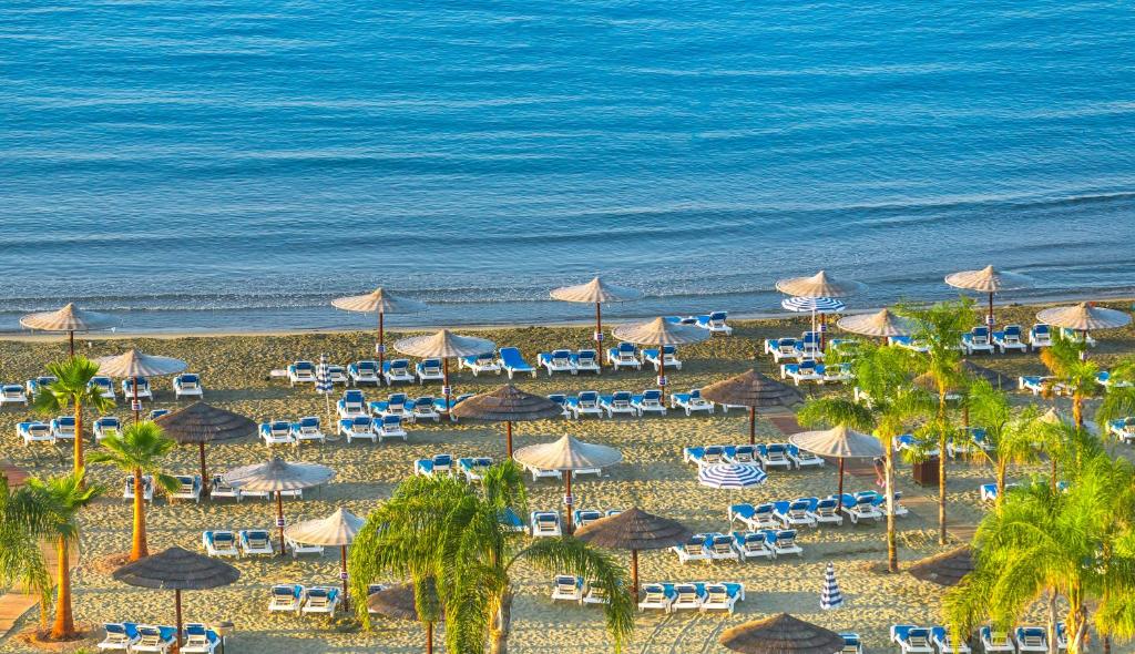 an aerial view of a beach with chairs and umbrellas at St Raphael Resort in Limassol