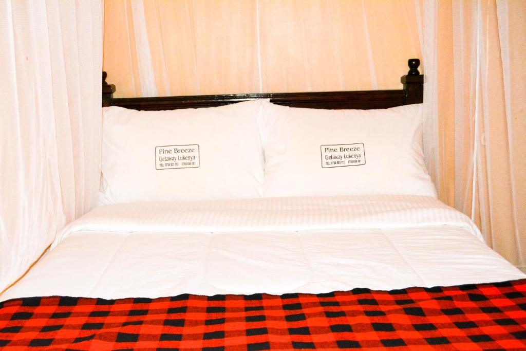 a bed with two white pillows and a checkered blanket at Pine Breeze Getaway Lukenya in Athi River