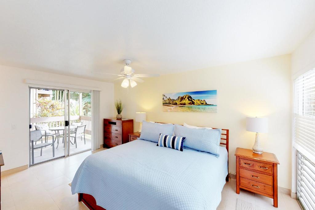 Dormitorio blanco con cama y mesa en Sandpiper #116b, en Princeville