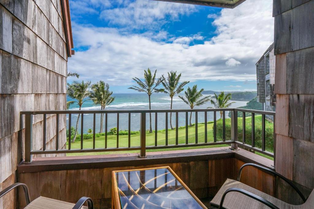 a balcony with chairs and a view of the ocean at SeaLodge in Princeville