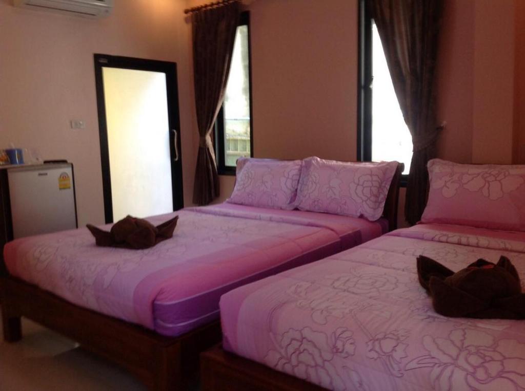 two beds in a room with pink sheets at Baan Mulan in Ko Samed