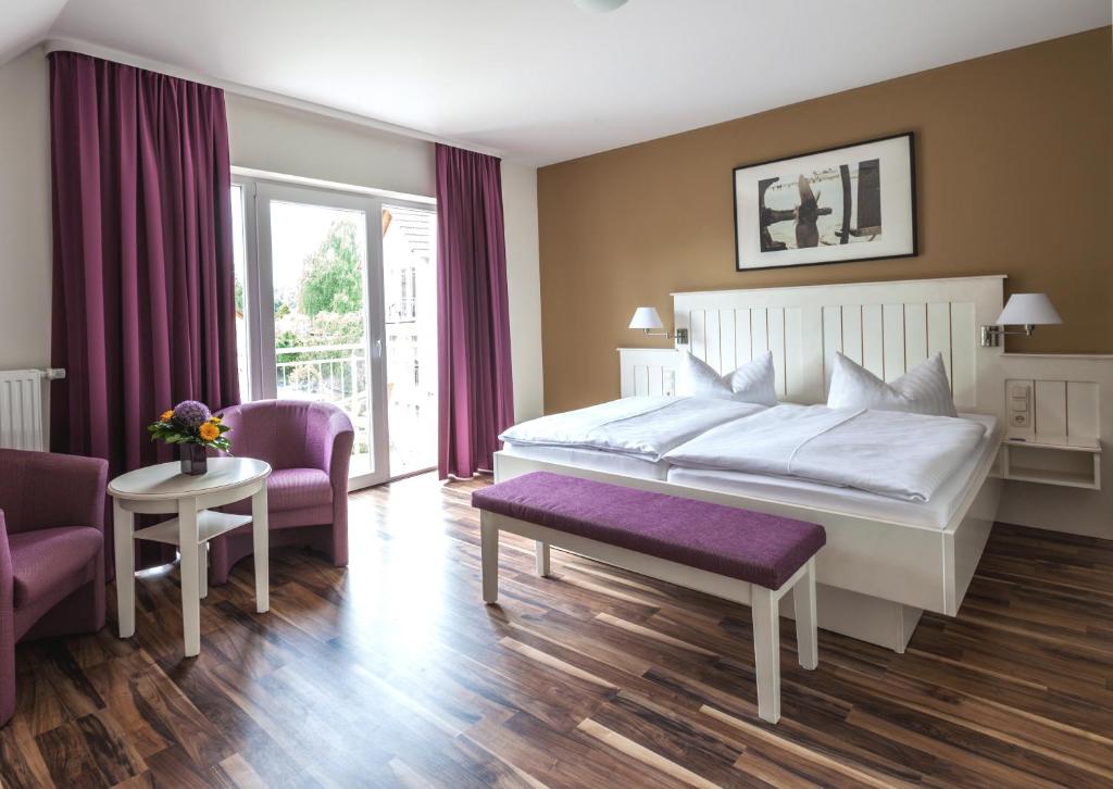 - une chambre avec un grand lit blanc et des chaises violettes dans l'établissement Pension Delia Will, à Ahlbeck