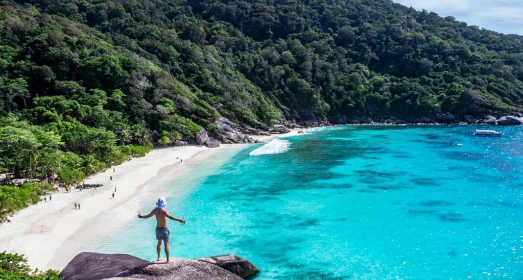 a person standing on a rock overlooking a beach at Best Rent a Room in Nai Yang Beach