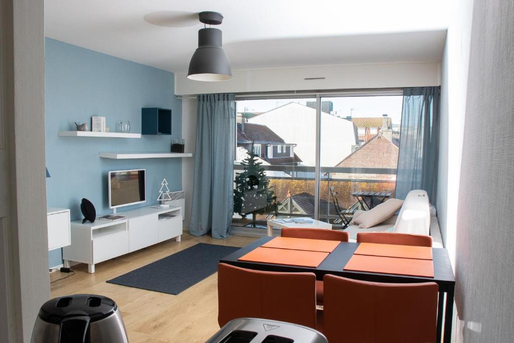 ein Wohnzimmer mit einem Tisch und Stühlen sowie ein Zimmer mit einem Fenster in der Unterkunft Charmant séjour au coeur du Touquet in Le Touquet-Paris-Plage