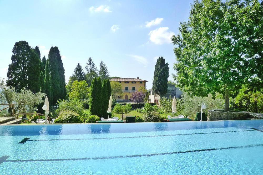 a large swimming pool with a house in the background at Fattoria I Tribbi in Ambra