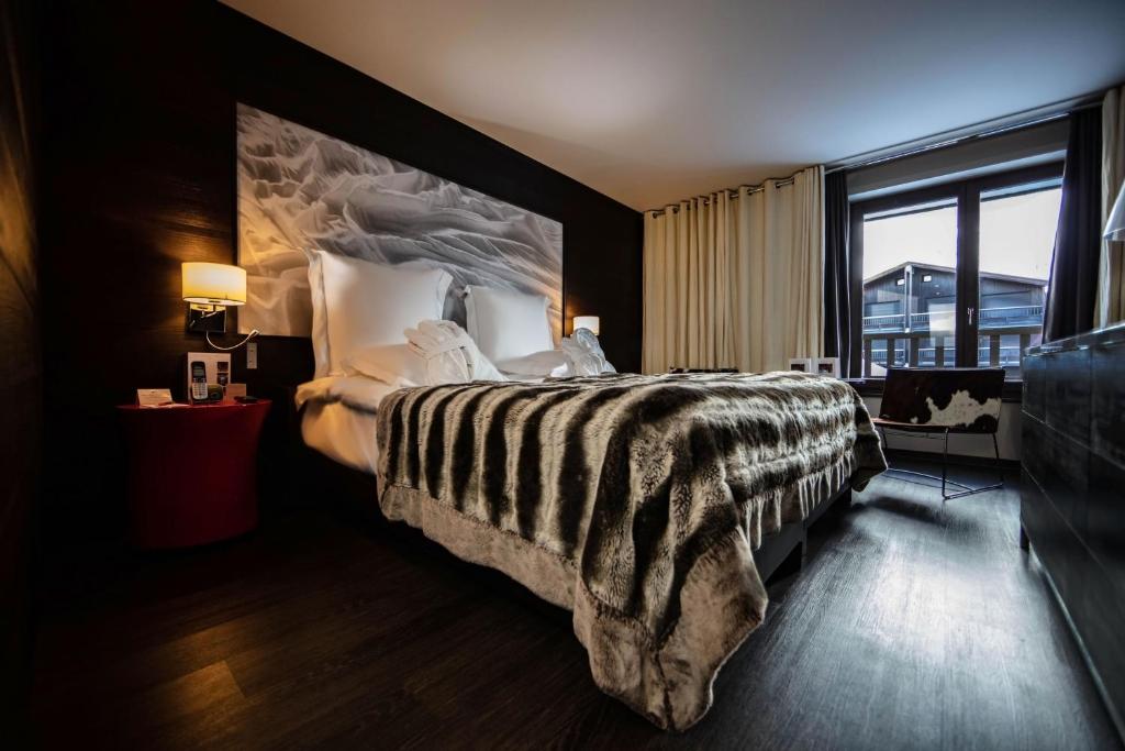 a bedroom with a large bed with a large window at Avenue Lodge Hotel & Spa in Val-d'Isère