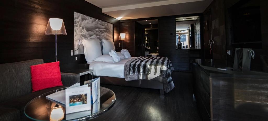 a hotel room with a large bed and a table at Avenue Lodge Hotel & Spa in Val-d'Isère