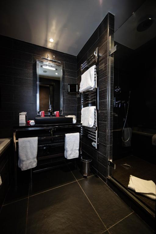 a bathroom with a sink and a bath tub with towels at Avenue Lodge Hotel & Spa in Val-d'Isère