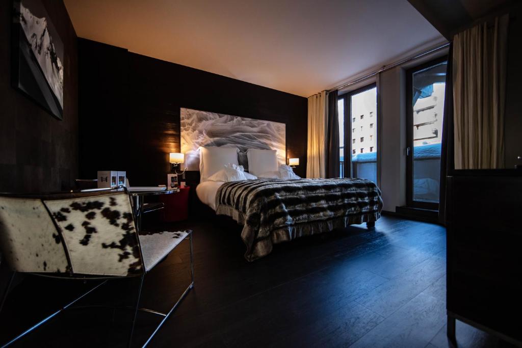 a hotel room with a bed and a large window at Avenue Lodge Hotel & Spa in Val-d'Isère