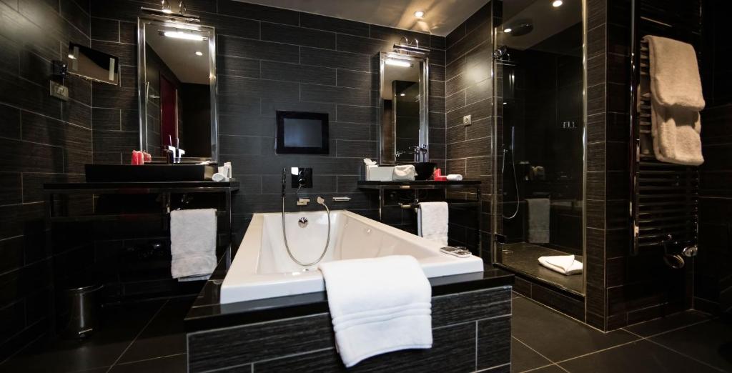 a black bathroom with a tub and a sink at Avenue Lodge Hotel & Spa in Val-d'Isère