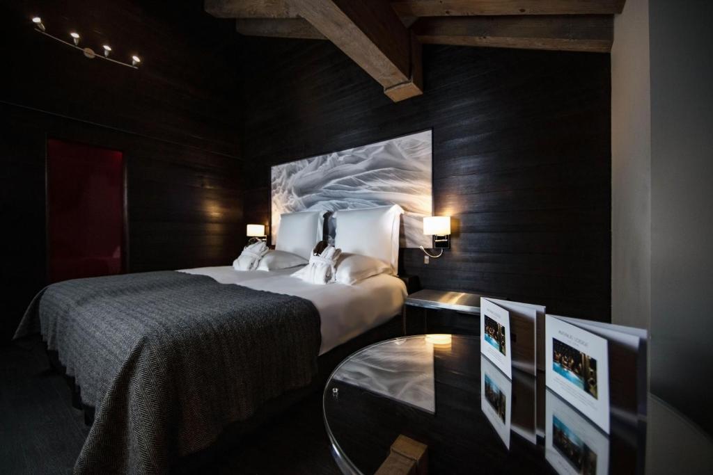 a bedroom with a bed and a table with two monitors at Avenue Lodge Hotel & Spa in Val-d'Isère
