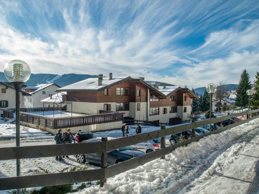 Un groupe de personnes debout dans la neige devant une maison dans l'établissement Hotel Villaggio Nevada, à Folgaria