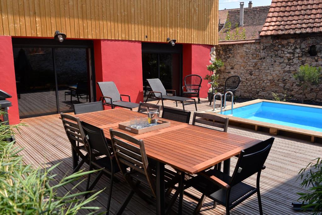 una mesa de madera y sillas en una terraza junto a la piscina en Bed`Zel Home, en Ingersheim