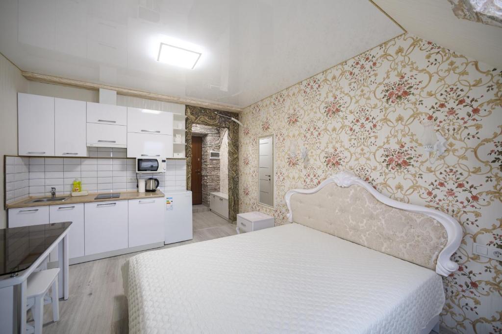 een slaapkamer met een wit bed en een keuken bij Apartments U Ratushi in Kamjanets-Podilsky