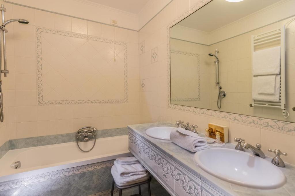 a bathroom with two sinks and a tub and a mirror at Hotel Giorgione in Venice