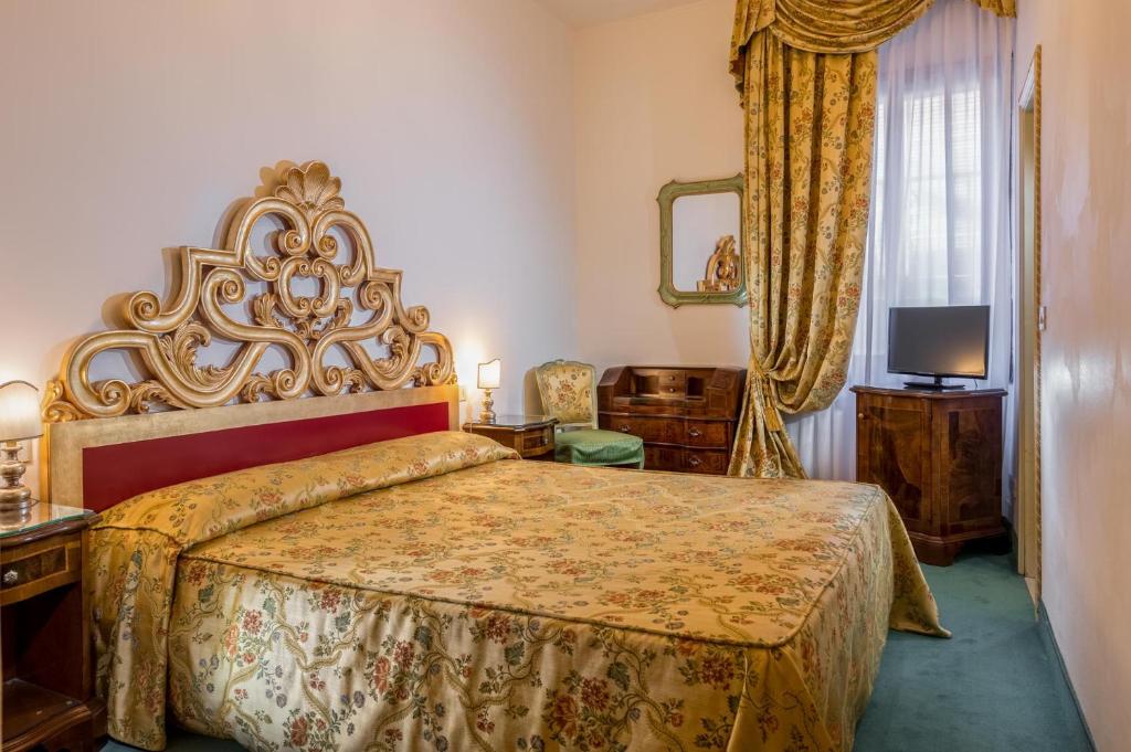 a bedroom with a large bed with a large headboard at Hotel Giorgione in Venice