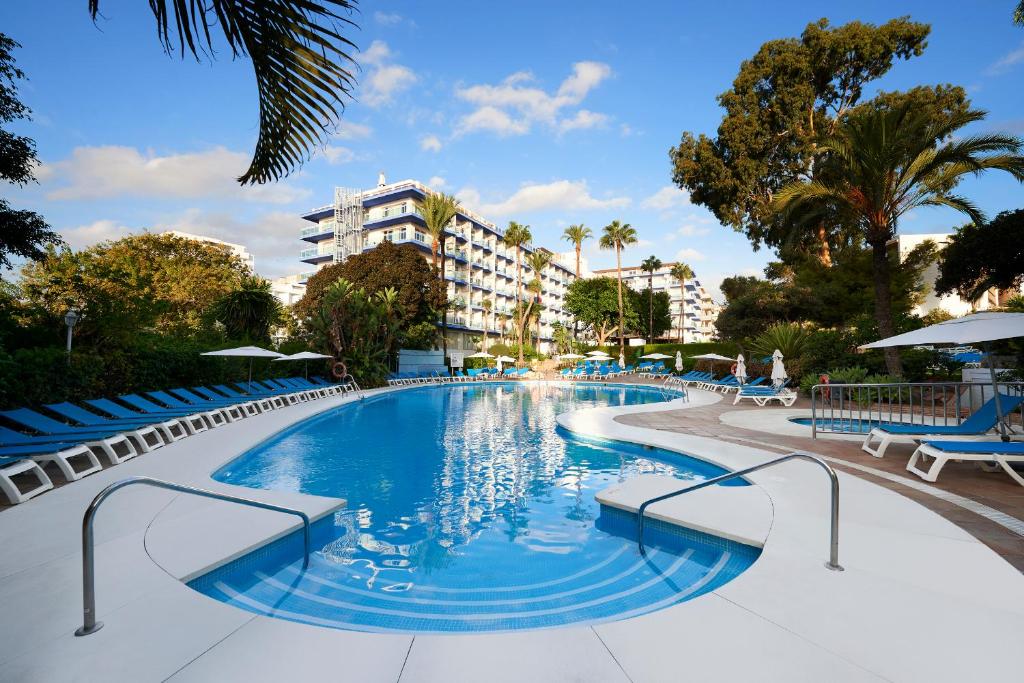 a large swimming pool with chairs and a building at Palmasol in Benalmádena