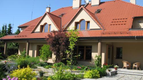 une maison avec un toit rouge et un jardin dans l'établissement American House Baletowa, à Varsovie