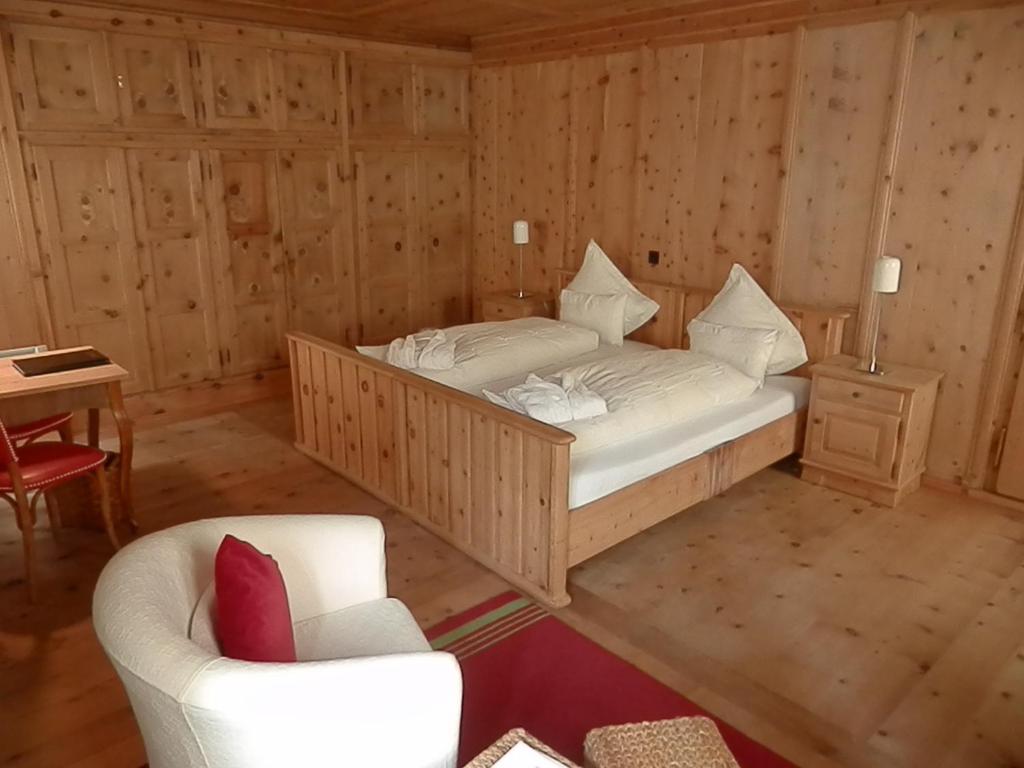 a bedroom with a bed and a chair and a table at Palazzo Mysanus Samedan in Samedan