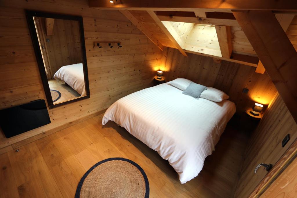 1 dormitorio en una cabaña de madera con cama y espejo en Chalet "Le mas devant" en Morillon