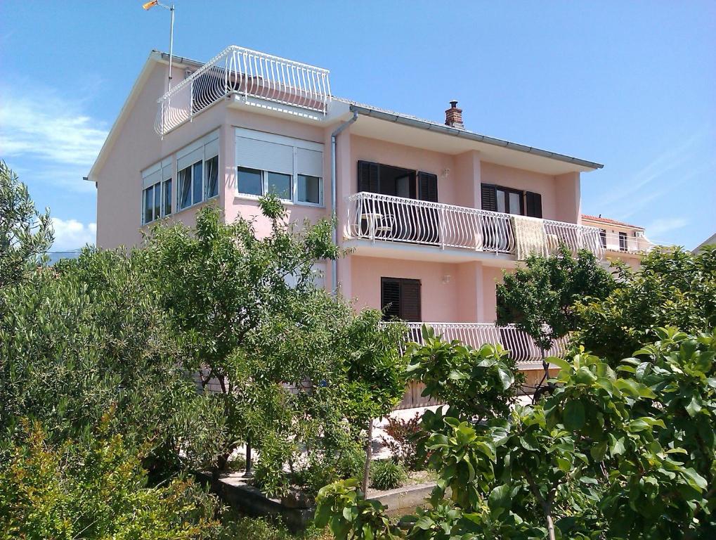 een roze huis met een balkon erop bij Rooms Marija in Barbat na Rabu