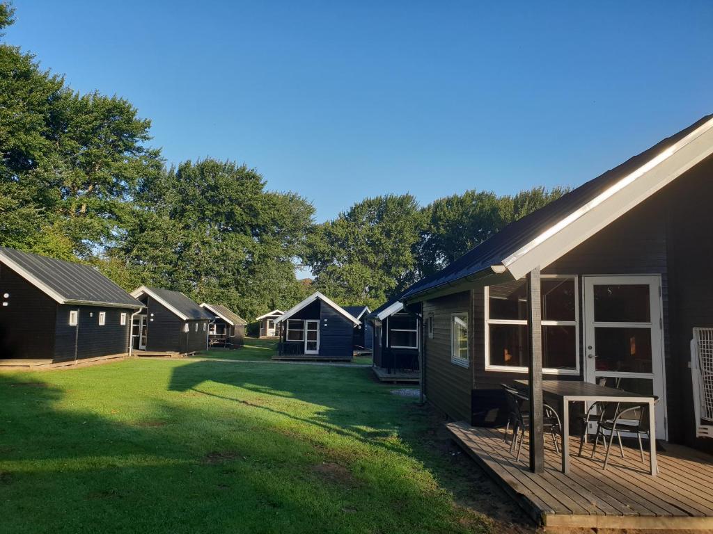 una fila de cabañas en un césped junto a una casa en First Camp Ajstrup Strand, en Malling