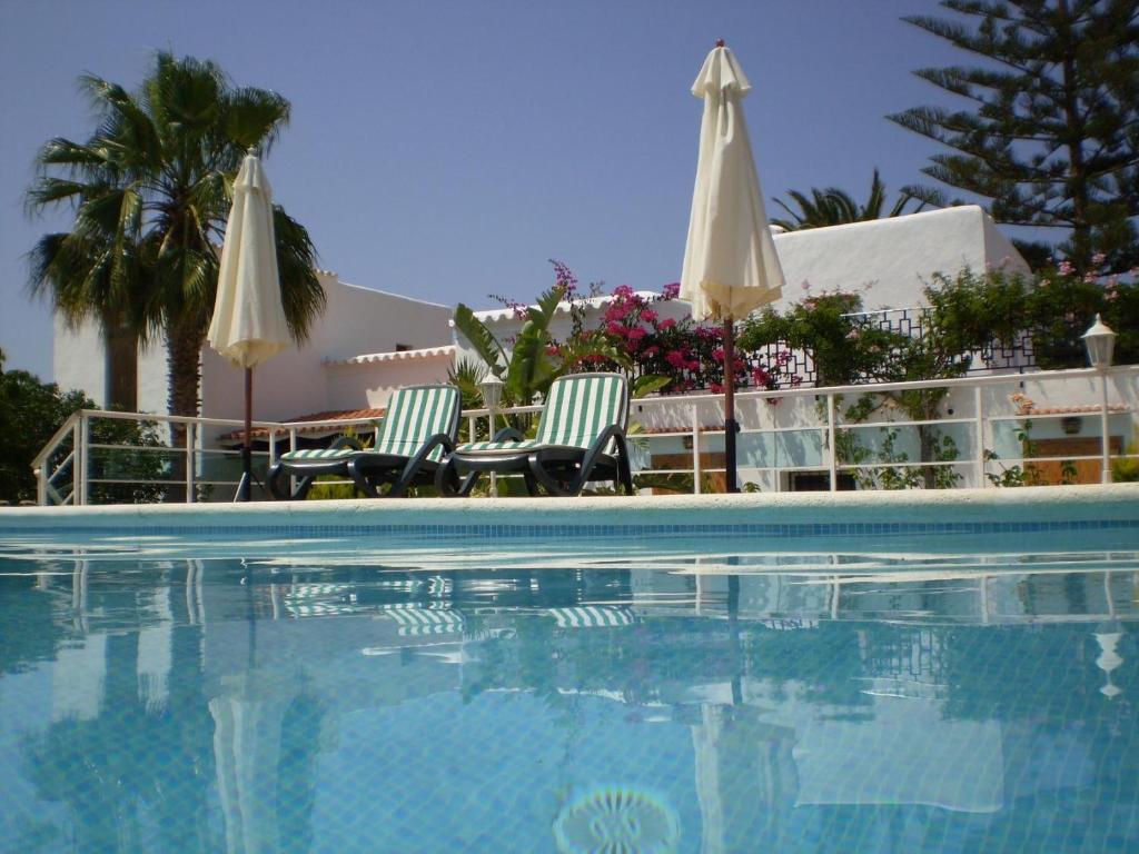 a swimming pool with two chairs and umbrellas at Can Joan Yern in Sant Joan de Labritja