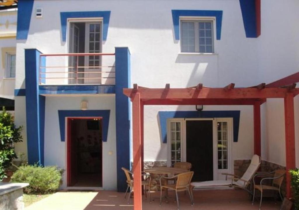 ein blau-weißes Haus mit einem Tisch und Stühlen in der Unterkunft Vivenda V3 Praia Verde in Castro Marim