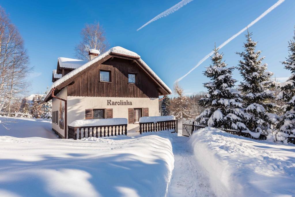 Una casa en la nieve con un árbol de Navidad en Ubytování Karolinka, en Prášily