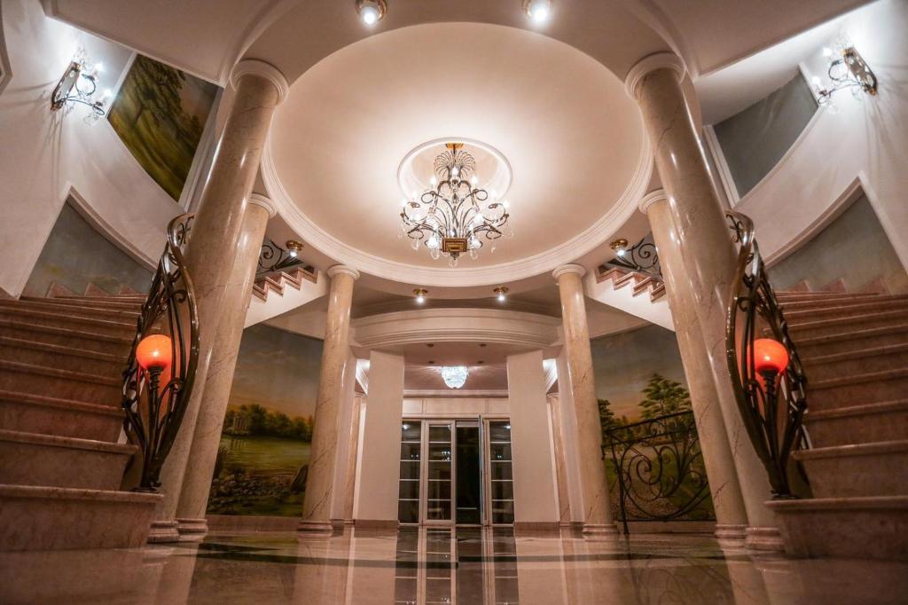 eine große Lobby mit einem Kronleuchter und einer Treppe in der Unterkunft Villa Dedinje in Belgrad