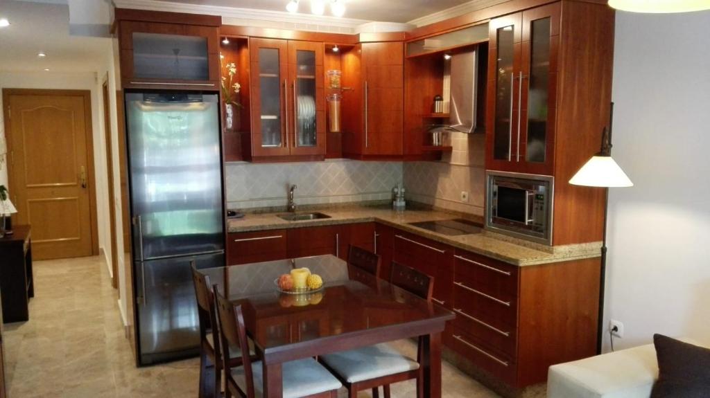 une cuisine avec des placards en bois et une table en bois avec une salle à manger dans l'établissement Apartamento en La Carihuela, à Torremolinos