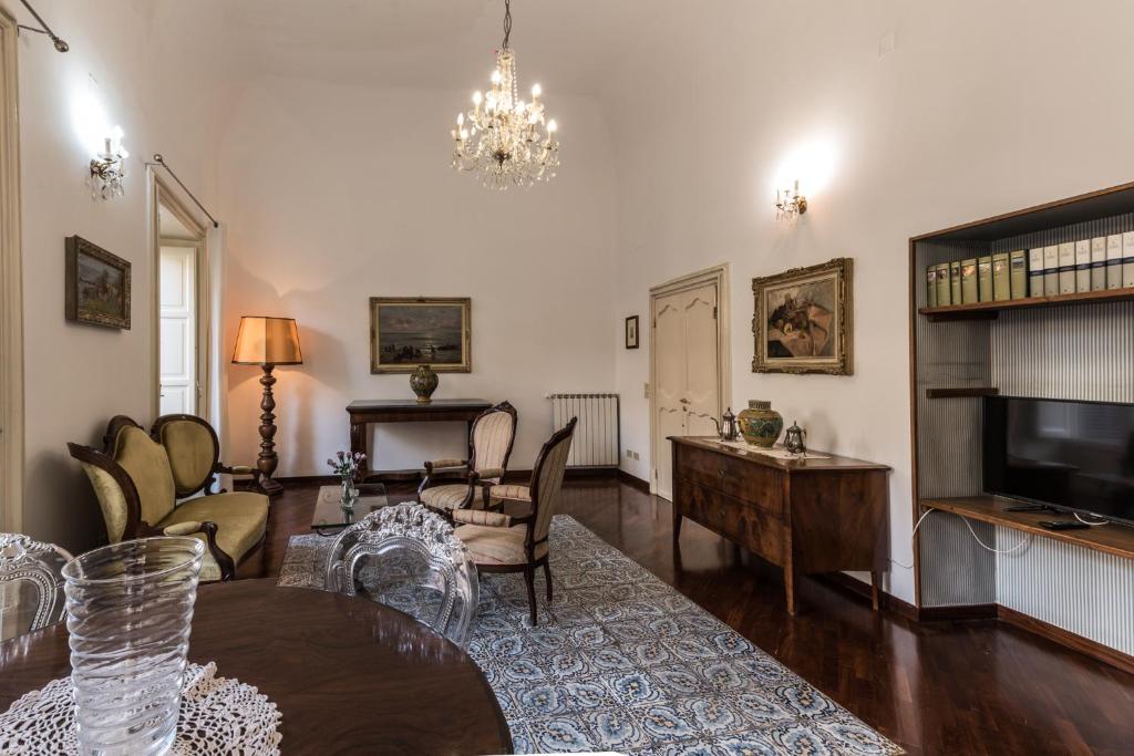 a living room with a table and chairs and a television at Appartamento Palazzo Pace al Cassaro in Palermo