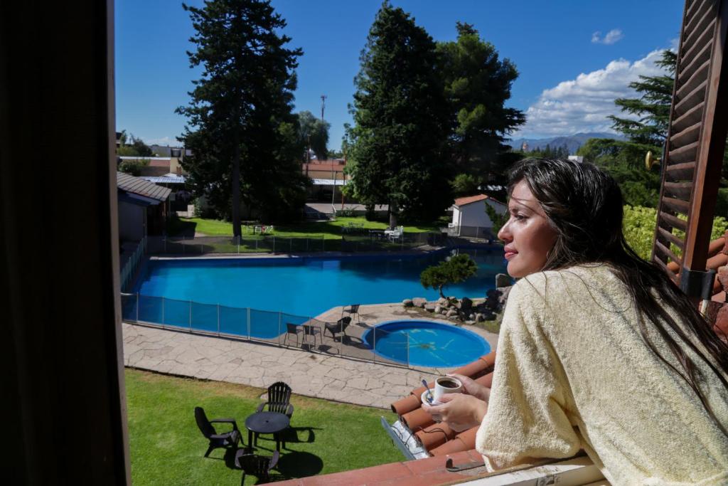 a woman sitting on a balcony looking out at a swimming pool at Hotel Dos Venados in San Luis