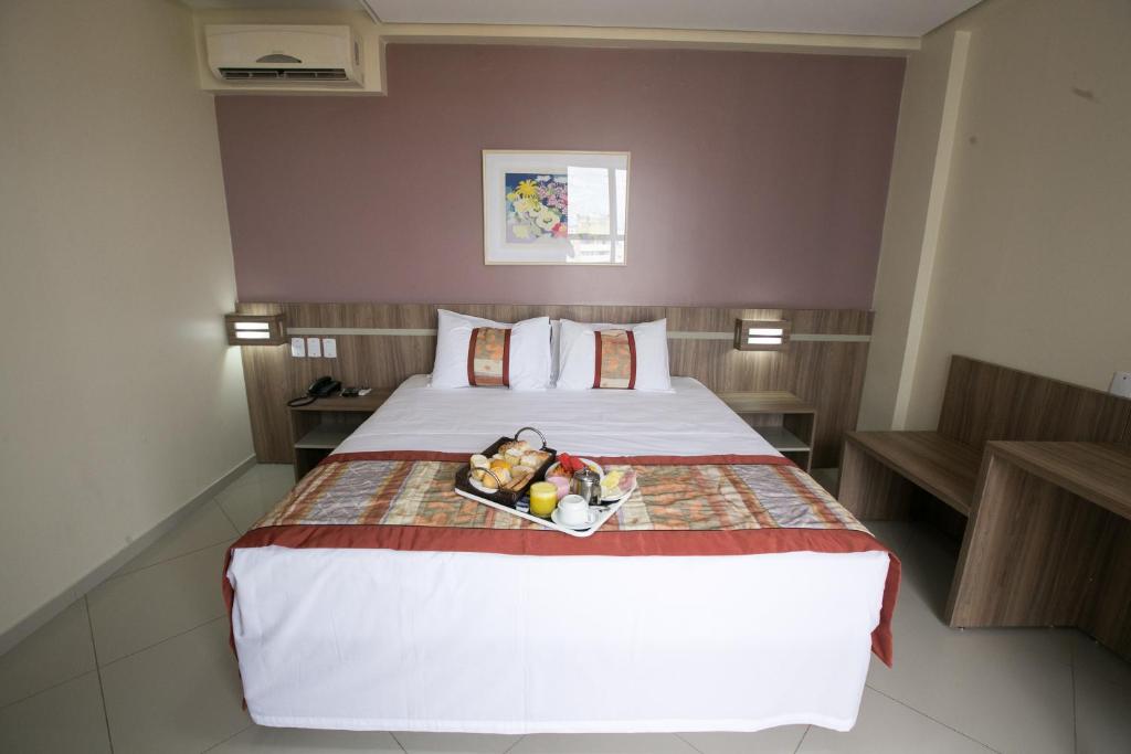 a bedroom with a bed with a tray of fruit on it at Paiaguas Palace Hotel in Cuiabá