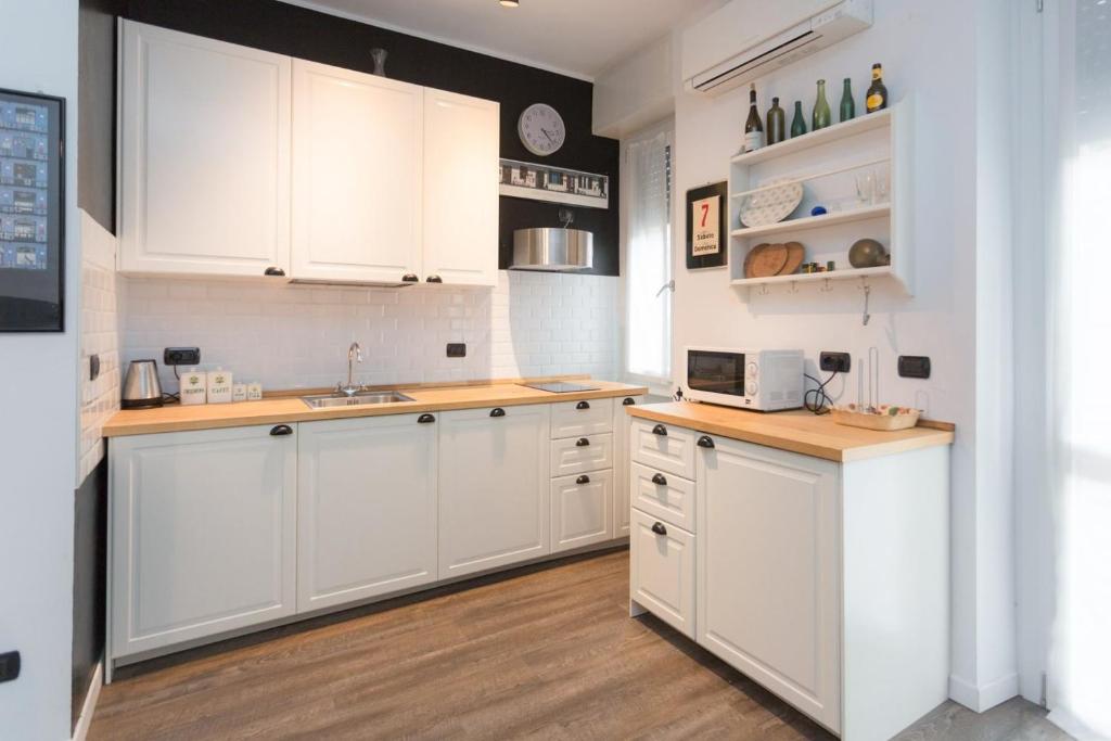 uma cozinha com armários brancos e pisos em madeira em Lust Studio Naviglio em Milão