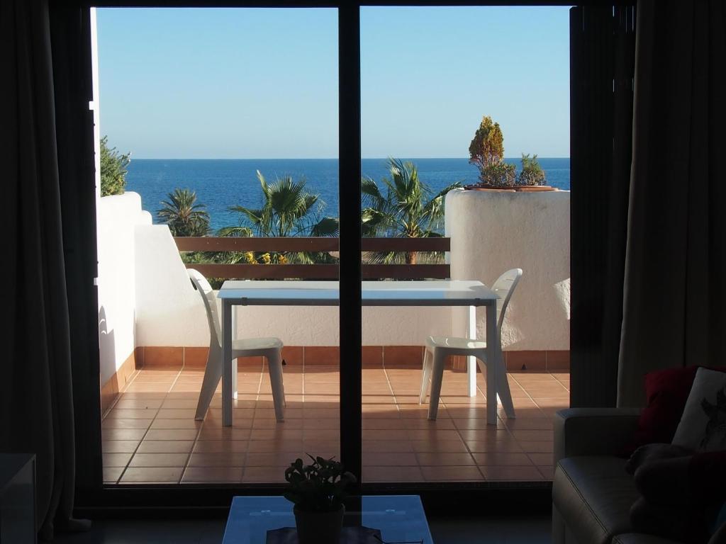 una mesa y sillas en un balcón con vistas al océano en Los Jazmines Frente Al Mar, en San Juan de los Terreros