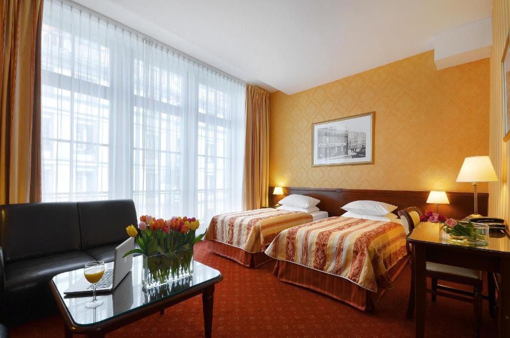 a hotel room with two beds and a couch at Hotel Wolne Miasto Old Town Gdańsk in Gdańsk