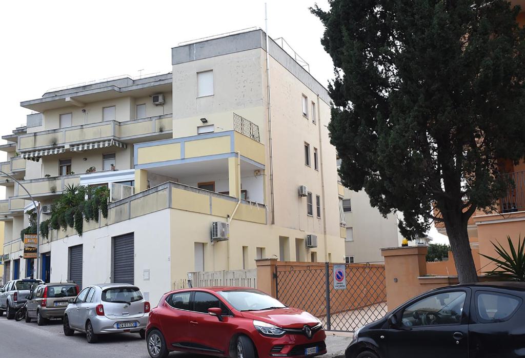 czerwony samochód zaparkowany przed budynkiem w obiekcie Kero House w mieście Alghero