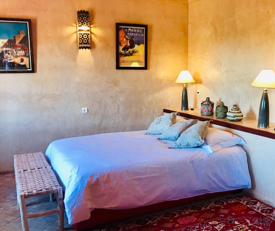 a bedroom with a bed and a table and two lamps at Hotel De Charme Les 3 Chameaux 4 étoiles in Mirleft