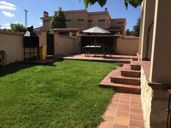 a backyard with a patio with a table and an umbrella at El Amanecer de la Sierra in Casla